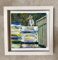 A framed painting by artist Mary Oh featuring a white heron standing above stacked fish boxes, displayed against a textured beige wall.